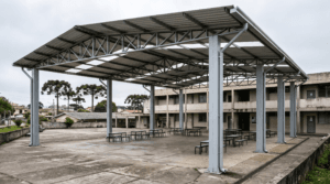 Cobertura metálica com tesouras e telha trapezoidal sobre pátio de escola e área de convivência - Metal Apex